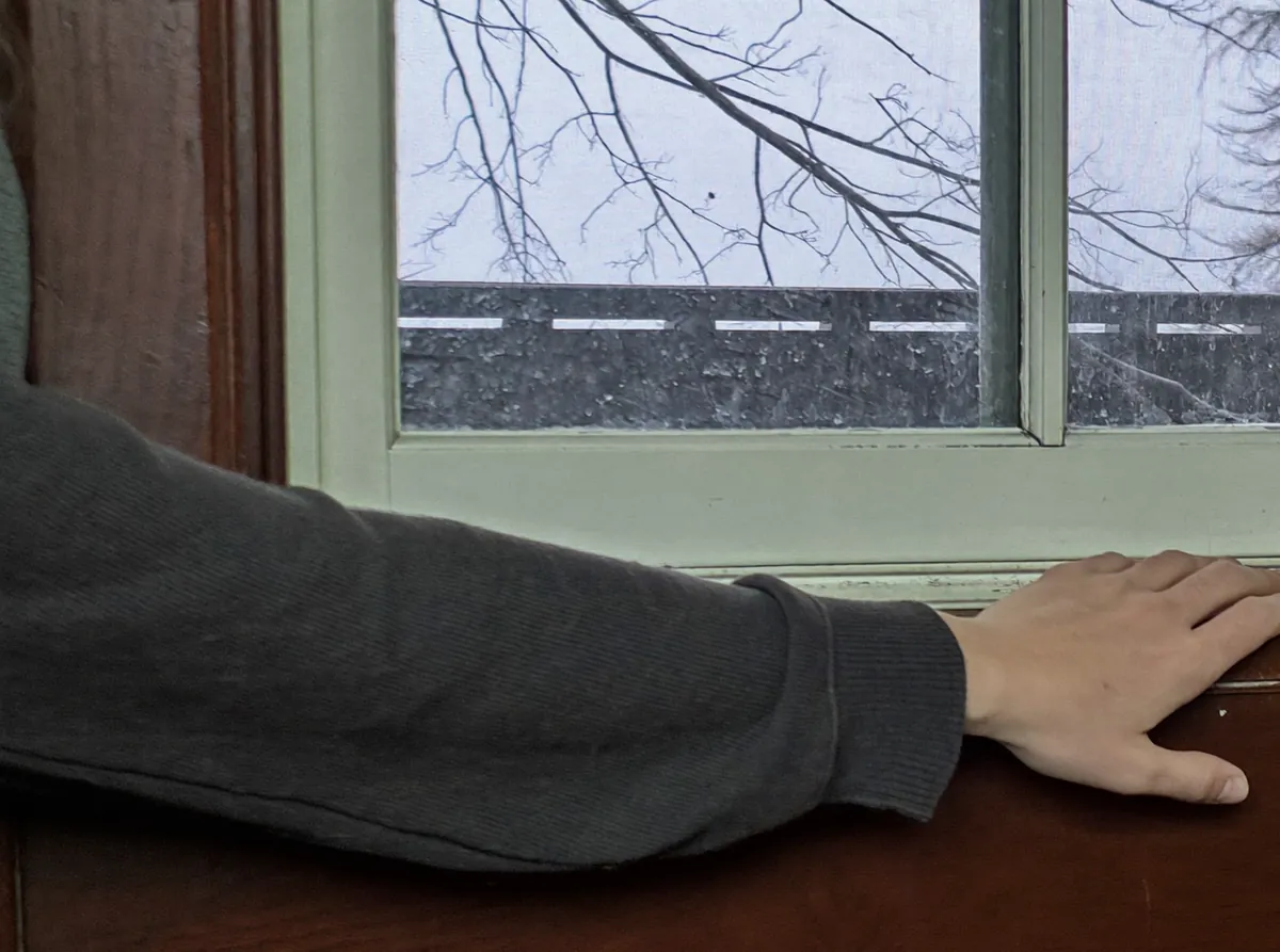 Homeowner at an old wood double-hung window in a home in Chicago, Illinois